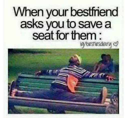 a man laying on top of a green park bench next to another person sitting down