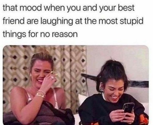 two women laughing and looking at their cell phones